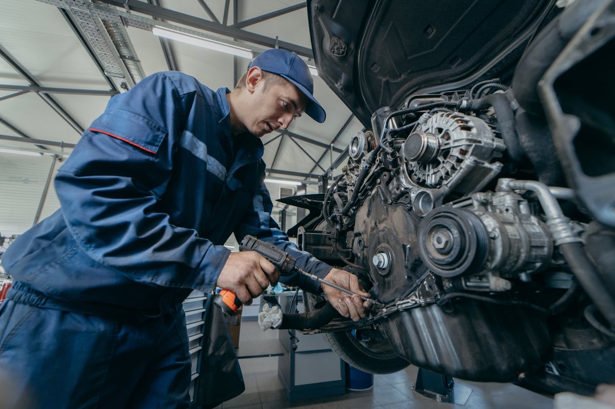 Mechanic inspecting a vehicle engine with diagnostic scanner